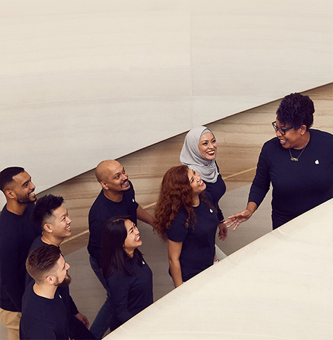 Członkowie zespołu wchodzący po schodach w sklepie Apple Store.