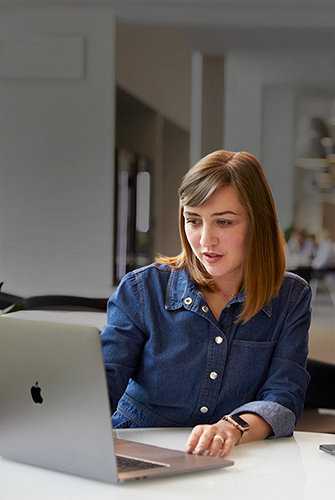 Iemand van het Support & Service-team van Apple is in een gemeenschappelijke ruimte op een MacBook aan het werken.