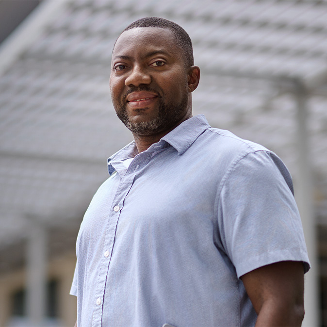  Photo de Kofi, debout, dehors et souriant à l’appareil photo.