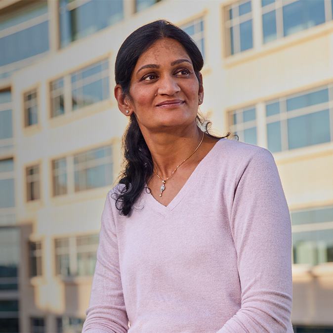 Photo de Ramani assise devant un bâtiment, le regard tourné sur le côté.