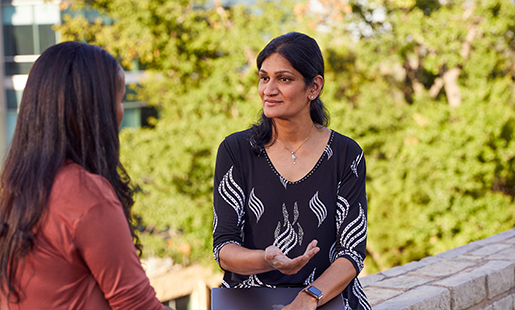 Ramani discute avec une collègue dehors, devant un paysage arboré.