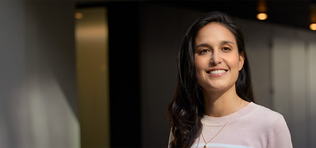 Camila egy irodában áll és mosolyog.