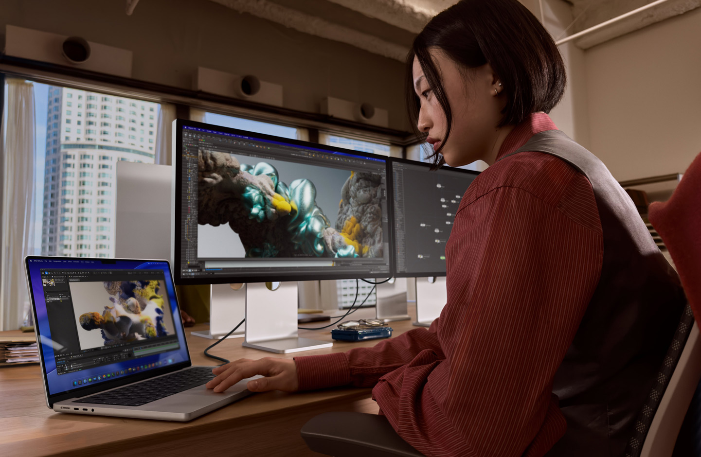 Pessoa a trabalhar num escritório com um portátil MacBook ligado a um Studio Display XDR por uma porta Thunderbolt 5