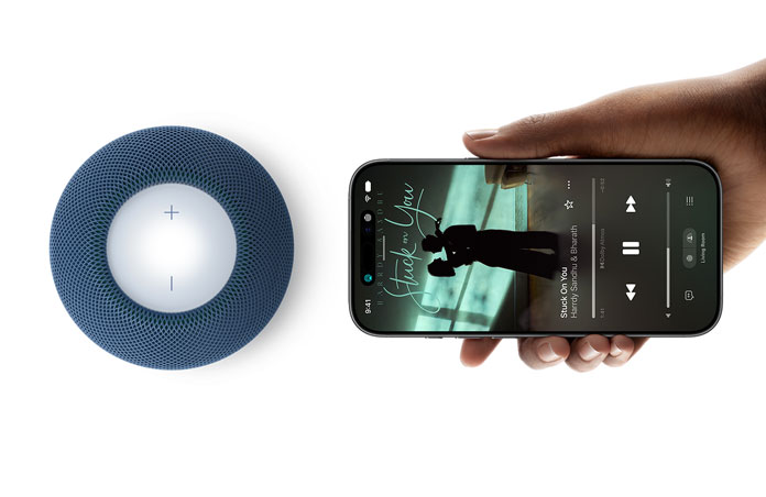 HomePod mini 2 and iPhone: A hand holds iPhone beside blue HomePod mini 2 for handoff feature