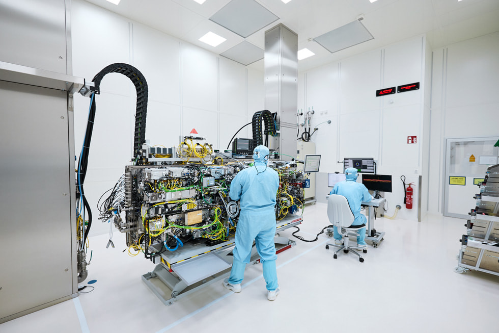 Two technicians at TRUMPF Ditzingen wearing protective clothing in a lab-like setting near a giant machine.