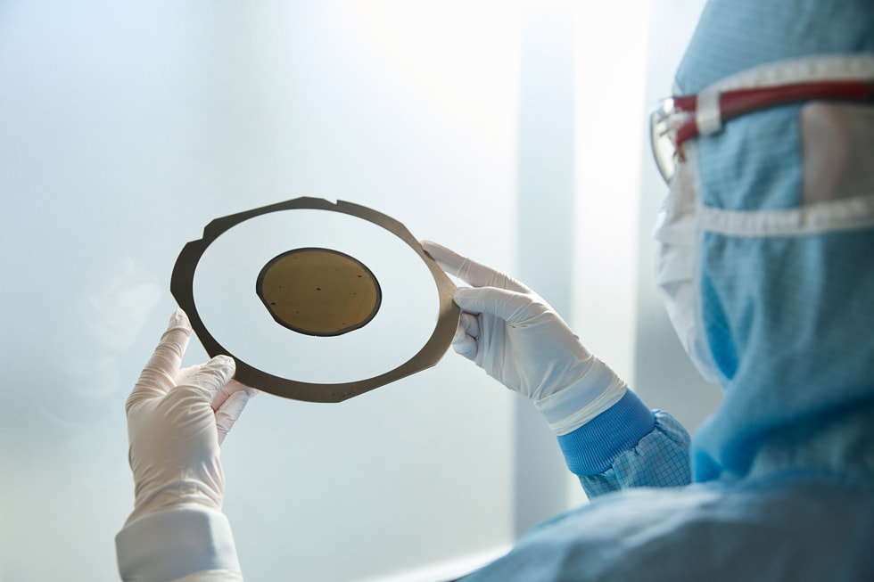 A worker wearing protective clothing examines a disc-shaped component at TRUMPF Ulm.