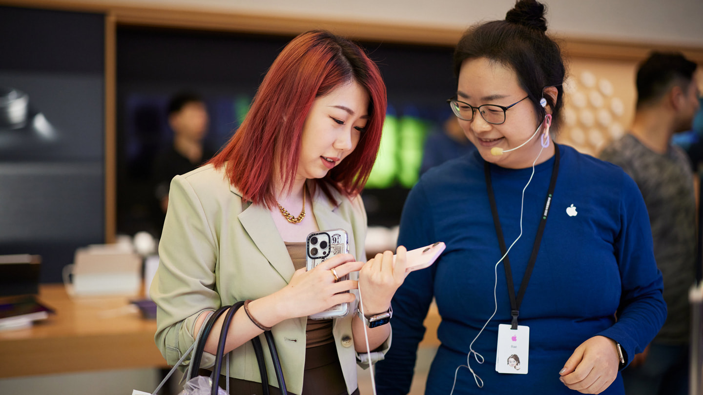 A customer holding the pink iPhone 15 while speaking with a team member at Apple Nanjing East.