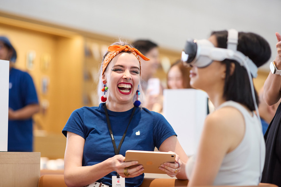 A team member smiles a huge smile as a customer tries out Apple Vision Pro.