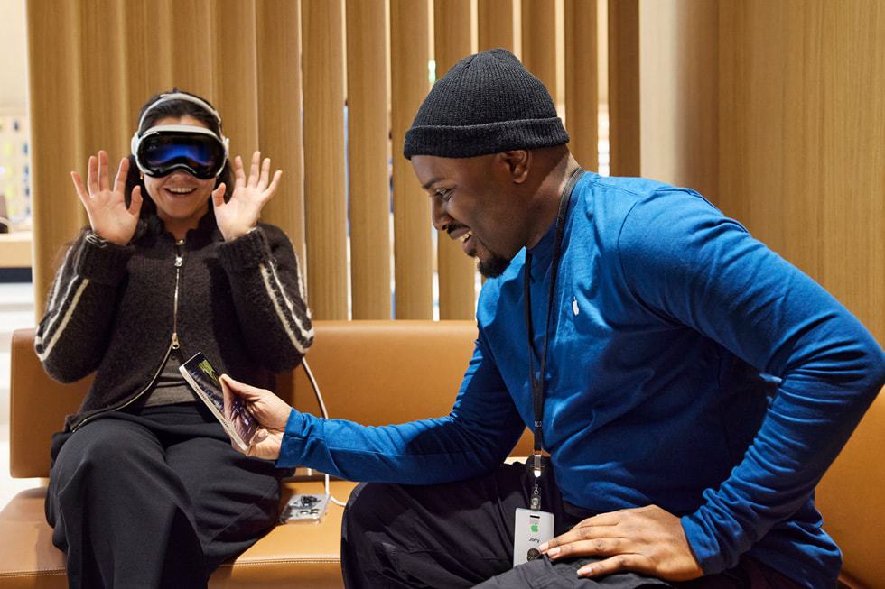 A customer wearing Apple Vision Pro listens to an Apple team member.