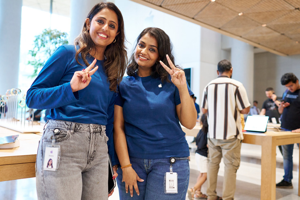 Two team members smile and hold up a peace sign at Apple BKC in Mumbai.