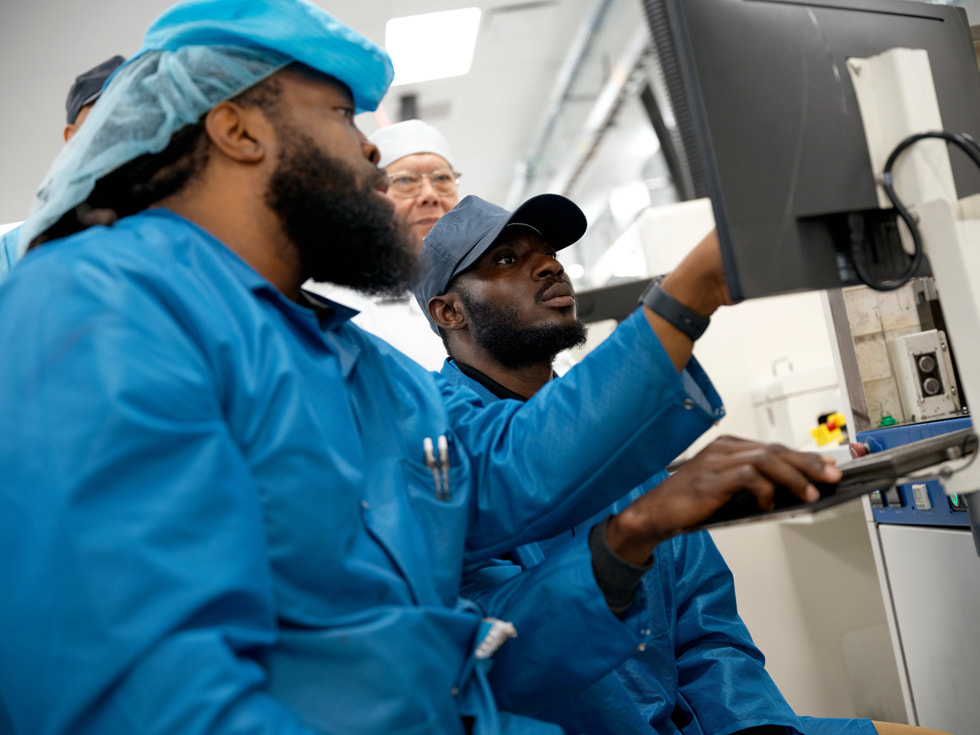 Technicians in protective clothing look at a monitor in a Houston factory.