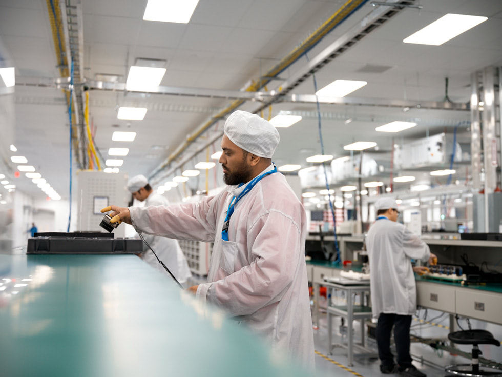 Technicians in protective clothing assemble logic boards in a Houston factory.