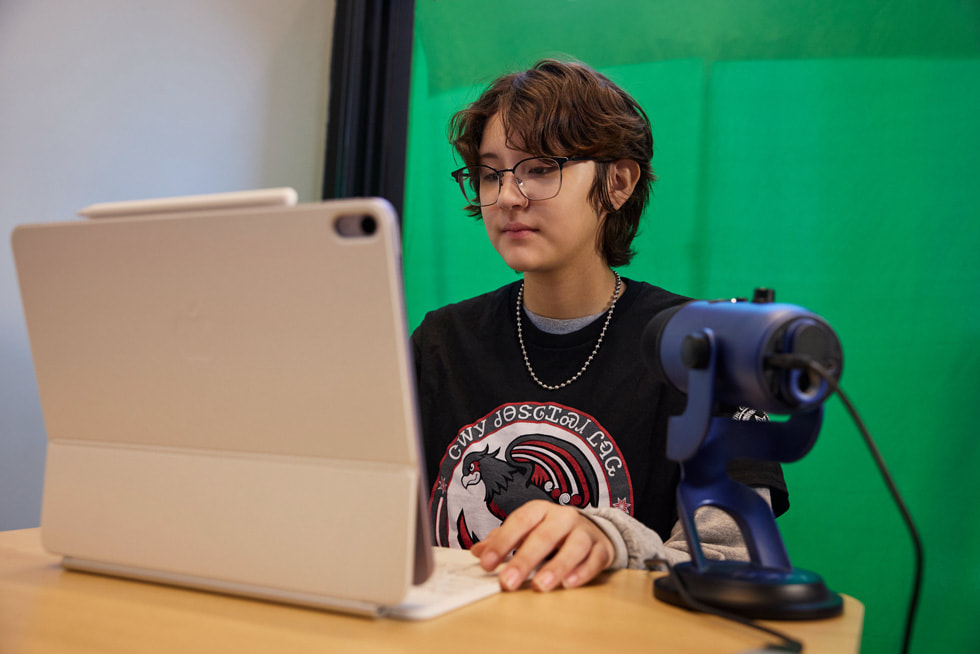 ภาพนักเรียนขณะกำลังใช้งาน iPad โดยมีไมโครโฟนวางอยู่บนโต๊ะ
