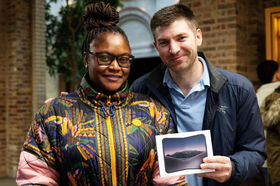 At Apple Covent Garden, a customer holds up a new iPhone Duo purchase next to another person.
