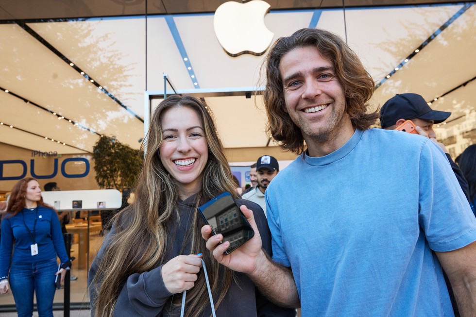 Two smiling customers at Apple Domain NORTHSIDE hold up a folded iPhone Duo.