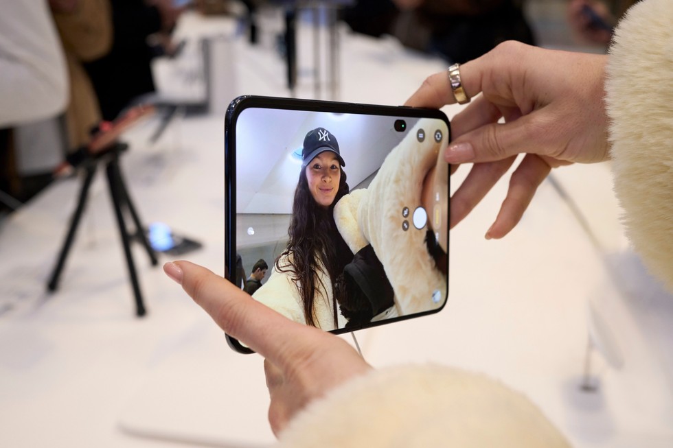 A close-up of a customer’s hands holding an unfolded iPhone Duo.