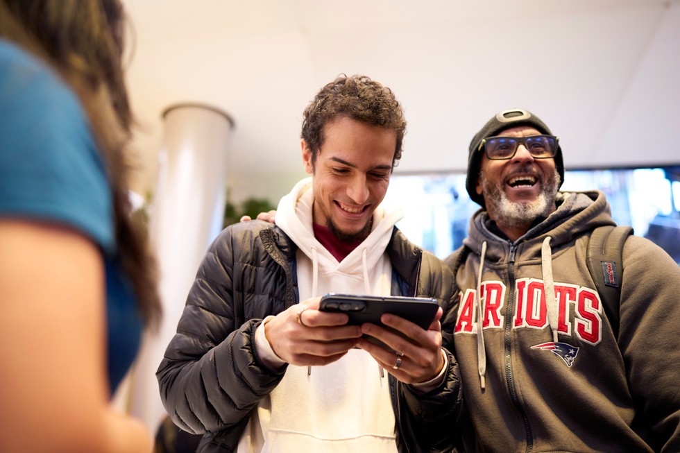 At Apple Fifth Avenue, a customer looks at iPhone Duo while another customer smiles.
