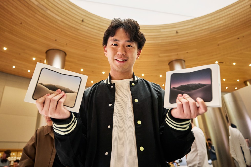 A customer smiles while holding two boxed iPhone Duo devices at Apple Jing’an.