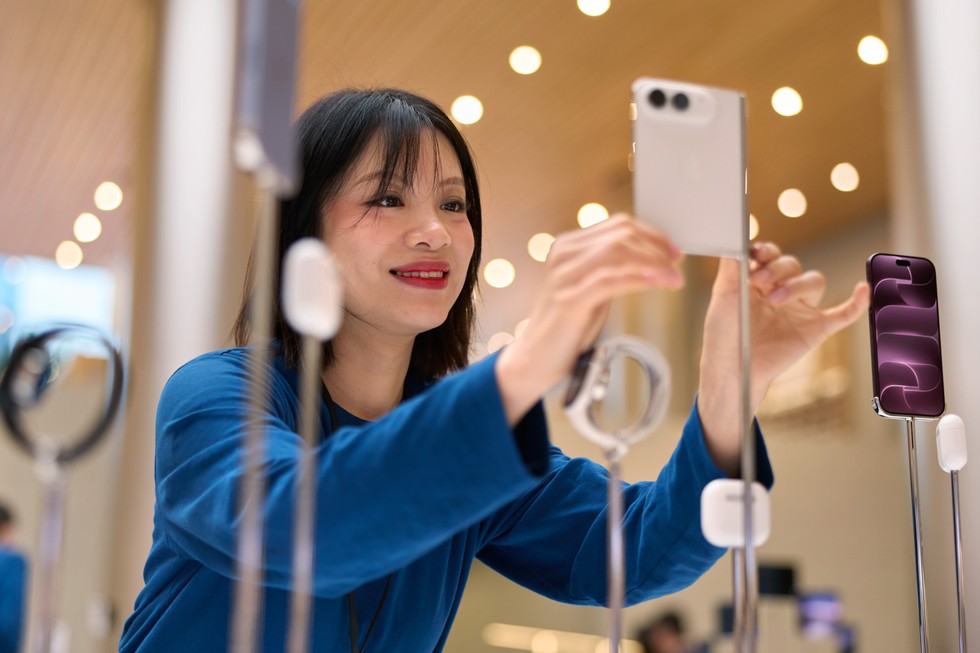 An Apple team member adjusts a star white iPhone Duo device on display at Apple Jing’an.