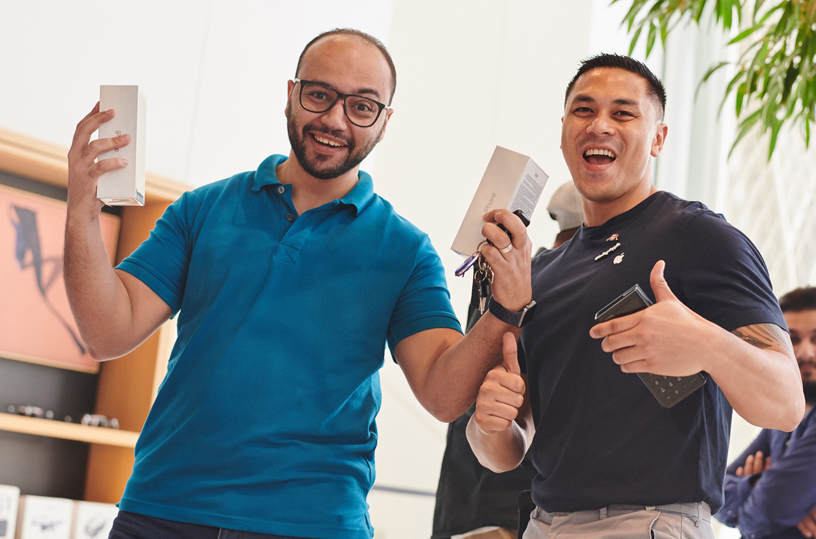 Customer holding up two iPhone Xs boxes with an Apple team member.