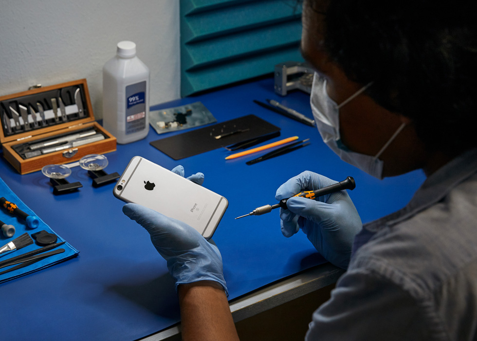 A repair technician performs a repair on an iPhone.