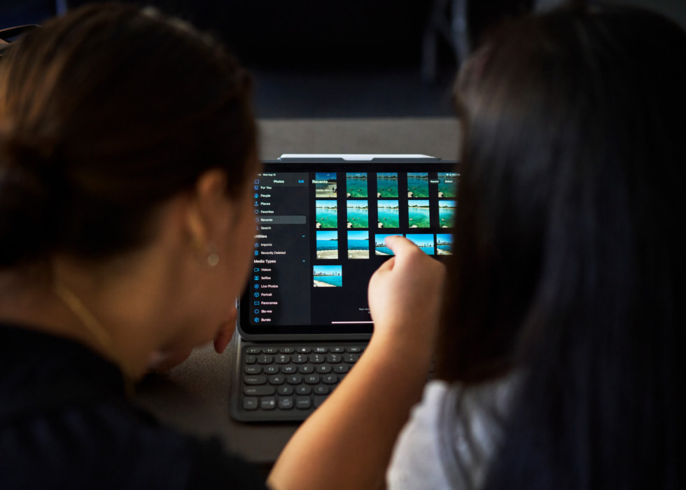 Se muestra a dos personas desde atrás que usan un iPad para editar fotos.