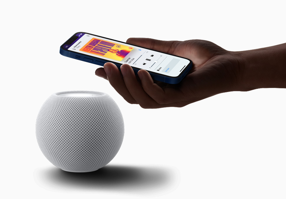 A customer holding iPhone 12 close to HomePod mini.
