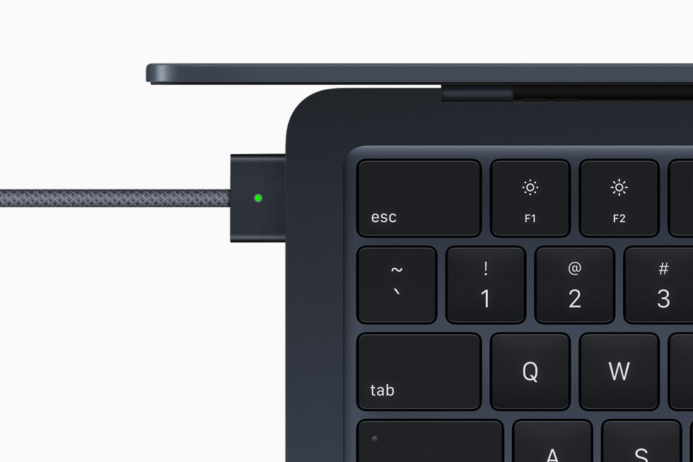 Closeup shot of MagSafe adapter plugged in to MacBook Air in midnight.