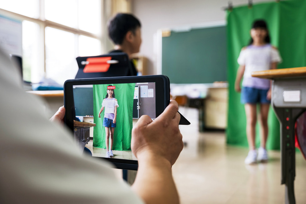 児童が教室でiPadを使って、クラスメートのビデオを撮影しています。