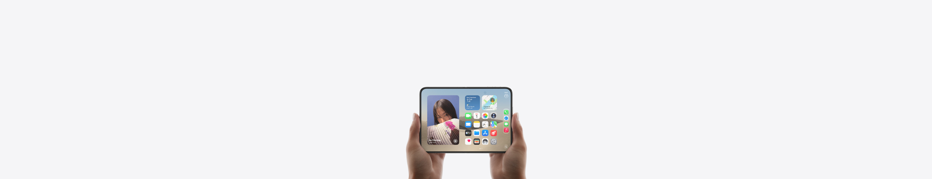 iPhone Duo, held by two hands in landscape orientation, unfolded, interior display features Home Screen.
