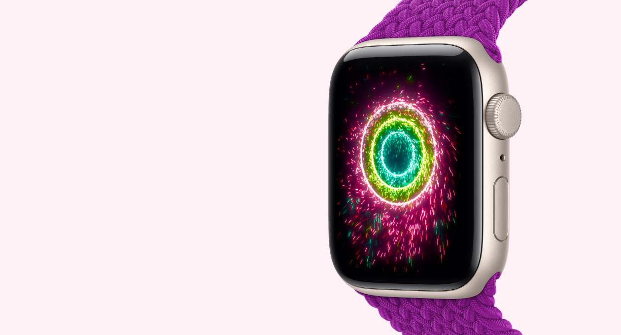  ساعة Apple Watch SE 3، إطار ألومنيوم، لون ضوء النجوم، شاشة تعرض حلقات النشاط على شكل ألعاب نارية، والجهة الخارجية اليمنى تُظهر قرص التاج الرقمي، ميكروفون، زر جانبي، حزام Loop أحادي مَجدول، لون ماجنتي