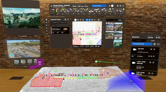 A 3D projection of dashboards for first responders shows camera feeds, team assignments and a 3D map of a parade route, in front of a brick wall inside an office