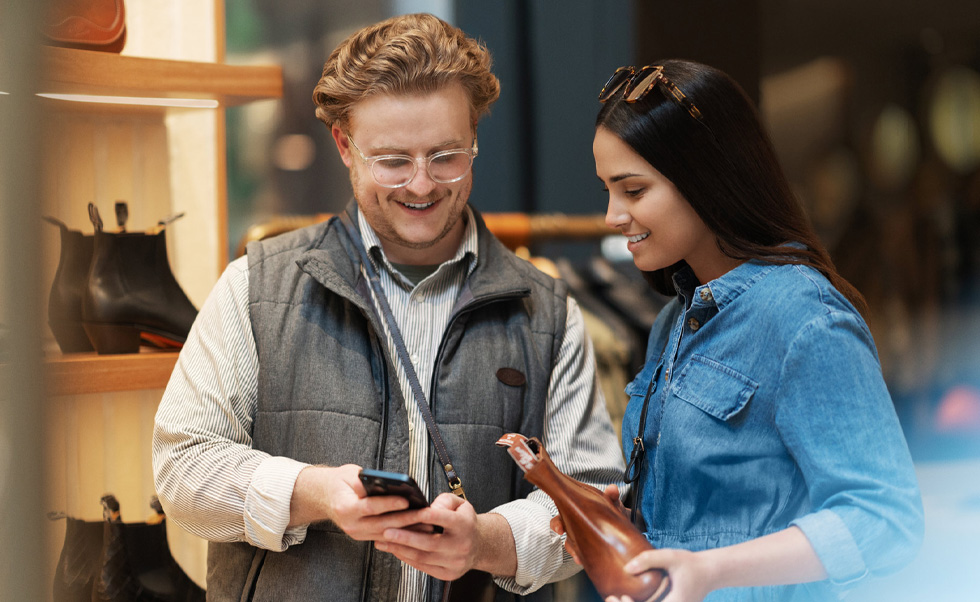 A sales assistant uses iPhone on the shop floor to help a customer.