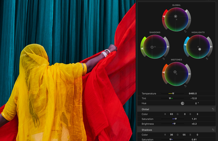 Screen showing woman in brightly colored yellow sari with red scarves against blue background, demo of color grading tools