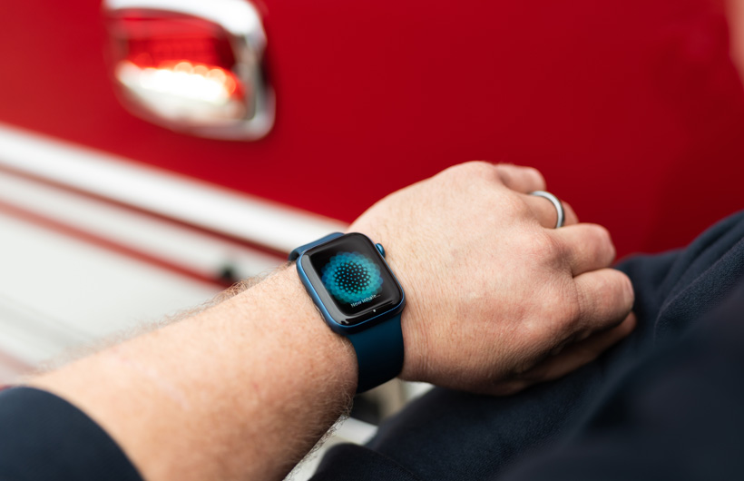 Accanto a un’autopompa, un uomo ha al polso un Apple Watch che mostra il messaggio: “Inspira…”