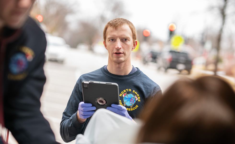 Un membro della squadra, con in mano un iPad, parla a una persona assistita in un veicolo per il trasporto medico