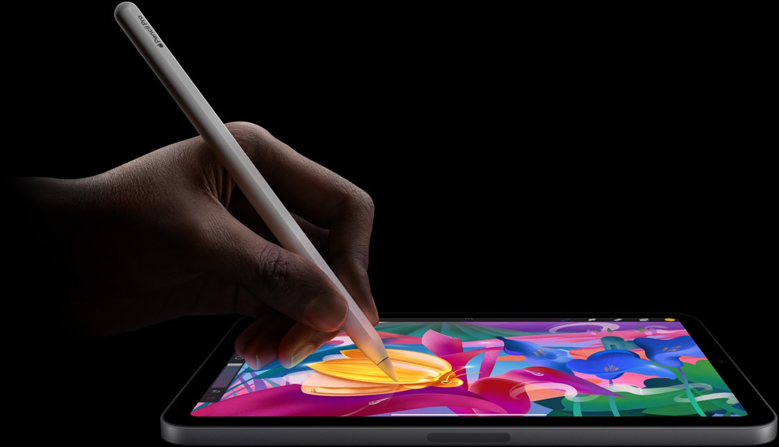 Apple Pencil Pro lietotāja rokā, veidojot krāsainu mākslas darbu iPad mini ekrānā.
